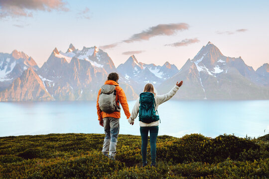 Couple in love hiking travel in Norway man and woman friends holding hands enjoying view, active vacations healthy lifestyle holidays tour outdoor family adventure mountaineering trip in Lyngen Alps