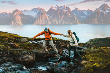 Couple man and woman hiking in Norway together in mountains family healthy lifestyle outdoor active vacations extreme adventure trip, friends trekking in Lyngen Alps - people crossing river in a wild