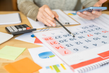 Office Desk with Business Schedule, Brainstorming Notes, and Project Plan. Hand Taking Notes for Corporate Strategy, Tasks, and Ideas in Reminder for Company Planning on Table.