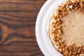 Piece of pumpkin or carrot layered cake with coconut and caramel cream and walnut. Vegan cake, sugar, gluten and lactose free. Top view, copy space.