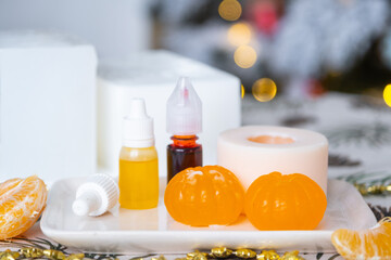 Handmade soap in the form of Orange tangerine  with bottles of dye, flavor, a block of glycerin soap base, silicone mold, on background of Christmas tree with golden light. Soap as gift new year