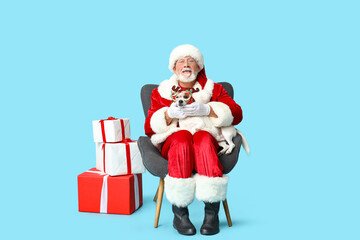 Santa Claus with cute Jack Russell Terrier dog in reindeer horns and Christmas gift boxes on blue background