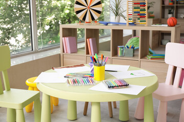 Felt-tip pens with paper sheets on table in kindergarten