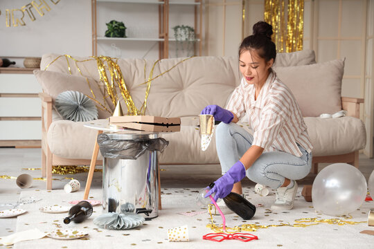 Young Asian woman picking up trash from carpet at home after Birthday party