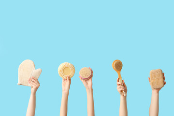 Female hands with bath sponges, glove and massage brushes on blue background