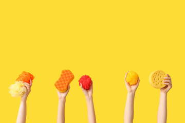 Female hands with different bath sponges on yellow background