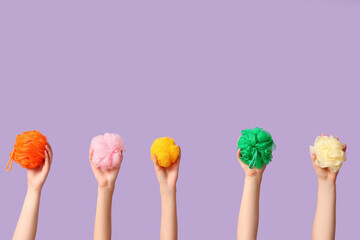 Female hands with different bath sponges on purple background