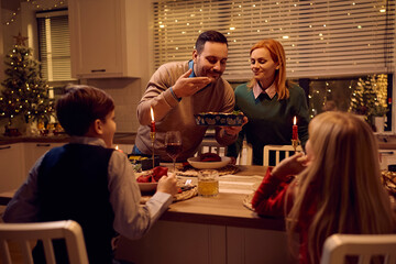 Happy man smelling food while serving Christmas dinner to his family at dining table.