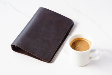 ミルクを入れたコーヒー、カフェ・ラッテを飲みながら、茶色の革のシステム手帳でデスクワーク中のイメージ
