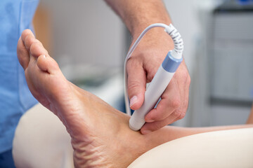 A physical therapist applies laser therapy to a patients ankle to reduce inflammation and promote healing. The focused light treatment is aimed at accelerating recovery from injury