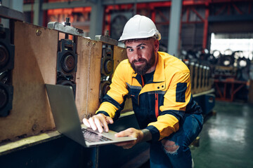 Engineer wear uniform and helmet using laptop are checking system machine at factory. Workers industrial factory. Machine maintenance technician operation concept.