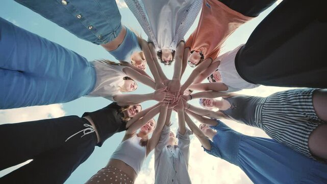 Group of young individuals gathering in a circle, linking hands in an outdoor team building activity