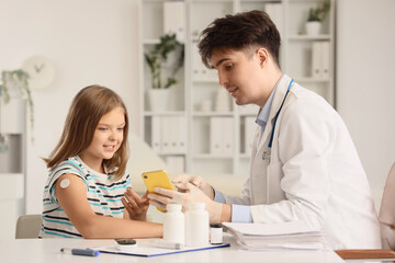 Fototapeta premium Diabetic girl with glucose sensor and doctor measuring blood sugar level in clinic