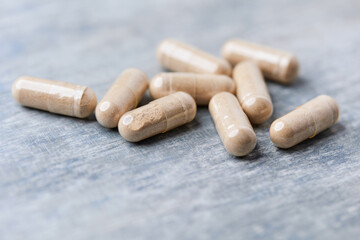 Reishi capsules. Concept for a healthy dietary supplementation. Wooden background. Soft focus. Close up.
