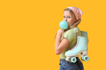Cute trendy girl with vintage roller skates blowing bubble gum on yellow background