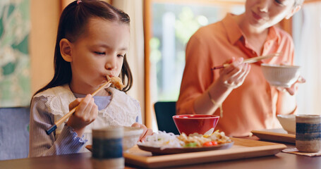 Mom, girl and chopsticks with eating, home or teaching for food, lunch or bonding with love in dining room. People, mother and daughter family house for meal, diet or nutrition with learning in Japan