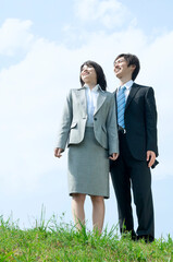 青空の下で遠くを見つめる男性と女性