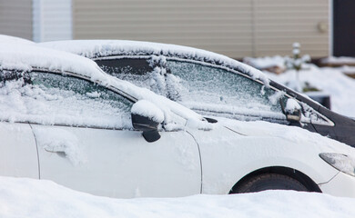 Two cars are covered in snow and have their windows frosted over