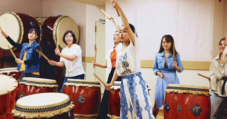 Japanese, drums and people in performance for music on instrument for stage practice, creativity or talent. Taiko, women and female drummers in band to play in rehearsal for culture, rhythm or beat