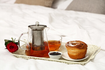 Tray with breakfast and rose for Valentine's Day on bed, closeup