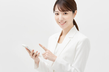 スマートフォンを操作する白いスーツ姿の女性