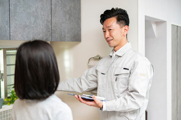 女性に説明する作業服姿の男性（水道業者）