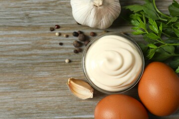 Bowl with mayonnaise and ingredients for cooking on wooden background
