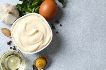 Bowl with mayonnaise and ingredients for cooking on gray background