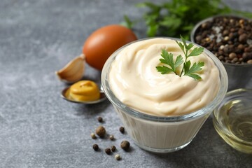 Bowl with mayonnaise and ingredients for cooking on gray background