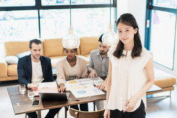 オフィスでポーズをするビジネスウーマンと国際色豊かなビジネスチーム