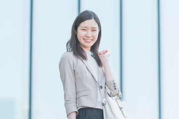 屋外で笑顔を見せるオフィスカジュアルスタイルの女性