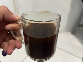 A Close-Up Shot of a Mug Filled with Dark Coffee, Held by a Hand with a Purple Nail Polish Accentuating the Rich Brown Hue of the Brew