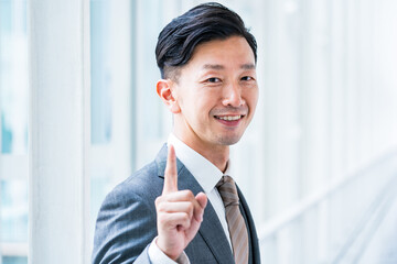 人差し指を立てるポーズをするビジネスマン