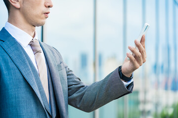 スマートフォンを持つスーツ姿の男性の手