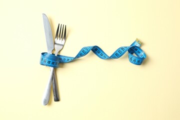Blue tape measure with cutlery on color background, top view.