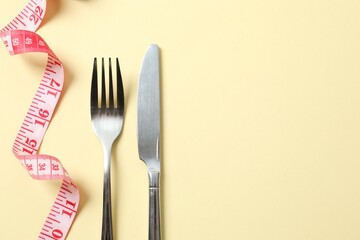 Red tape measure with cutlery on color background, top view.