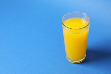Glass of freshly squeezed orange juice on color background 