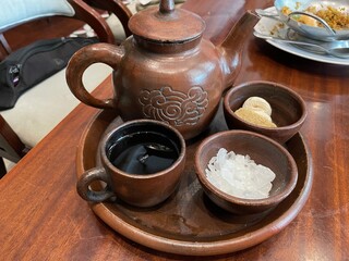 Traditional Clay Teapot Set with Sweeteners on Wooden Table in Restaurant Setting