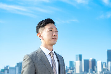 青空とビル群を背景にしたビジネスマンのポートレート