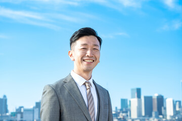 青空とビル群を背景にしたビジネスマンのポートレート