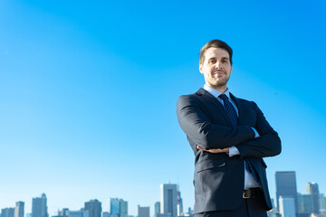 青空とビル群を背景にしたビジネスマンのポートレート