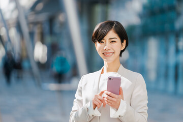 スマートフォンを持つスーツ姿の女性