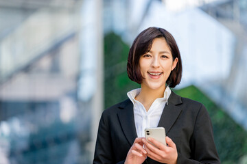 スマートフォンを持つスーツ姿の女性