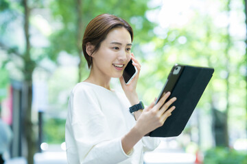 Fototapeta premium タブレット操作をしながらスマホで通話する女性