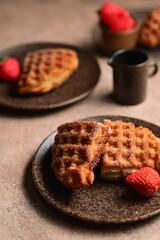 Breakfast menu with fresh baked delicious homemade croissant waffle croffle served on beautiful blue plates completed with strawberries, all put on wooden table.