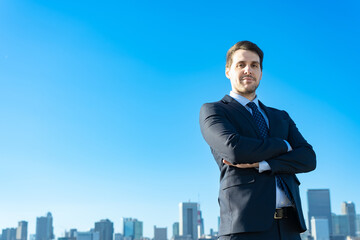 青空とビル群を背景にしたビジネスマンのポートレート