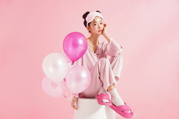 ピンク背景で撮影をしたパジャマを着た若い女性のキュートなポートレート