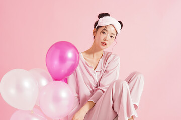 ピンク背景で撮影をしたパジャマを着た若い女性のキュートなポートレート