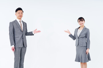 案内のポーズをするスーツ姿の男女