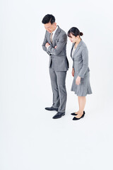 画面の下の方を見つめるスーツ姿の男女